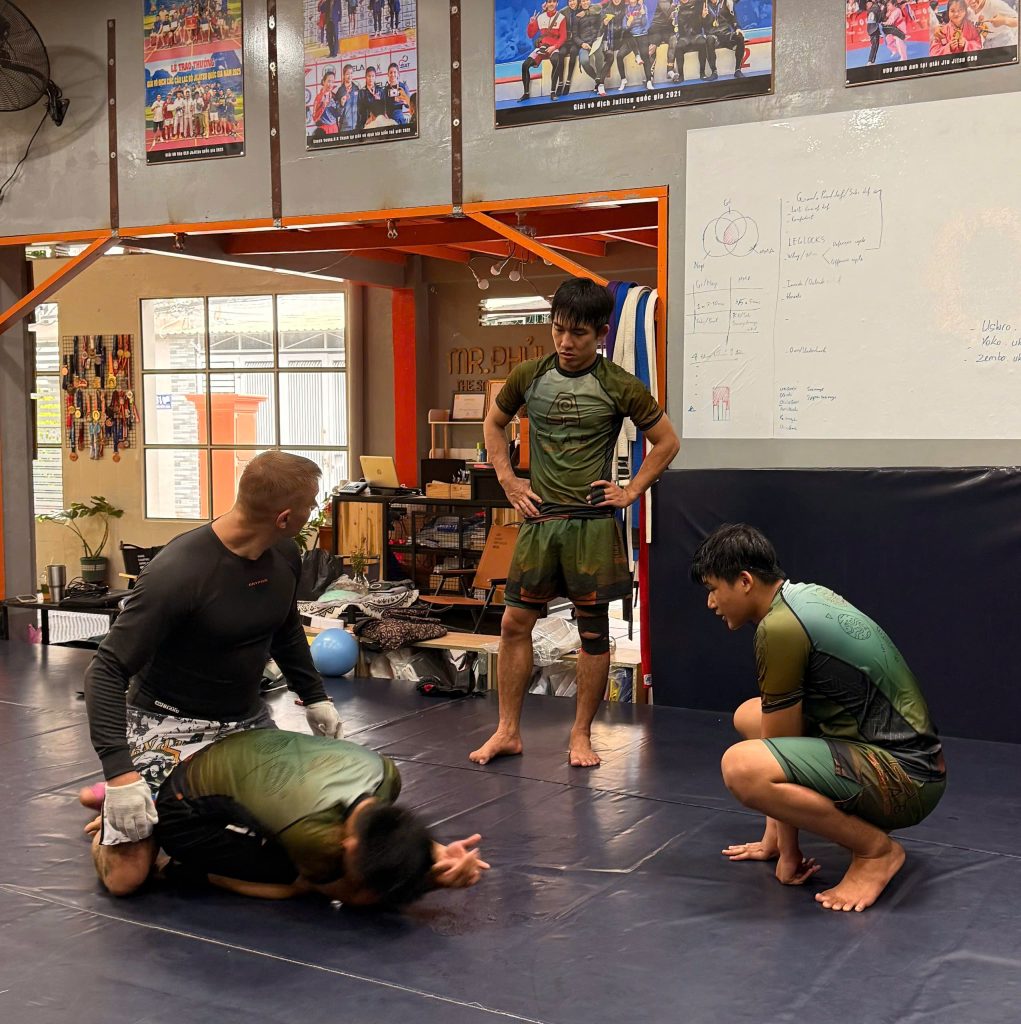 MMA students rolling on the mats during grappling session.